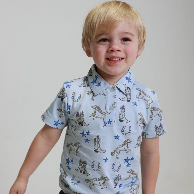 Child wearing a patterned shirt with cowboy design on a plain background